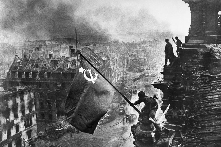 Бойцы 8-й гвардейской армии РККА Алексей Ковалев и Абдулхаким Исмаилов (слева направо) с красным знаменем на крыше здания Рейхстага после взятия города советскими войсками