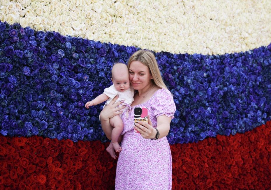 Девушка с ребенком на фоне триколора из бутонов живых роз в День России в Краснодаре