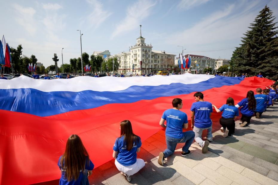 ЛНР. Луганск. Активисты «Молодой Гвардии Единой России» во время разворачивания флага Росиии на площади Героев ВОВ в День России