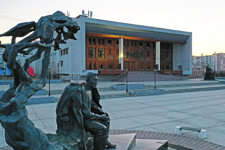 Что посмотреть в Якутске: памятник основоположнику якутской литературы А. Е. Кулаковскому (на первом плане) и Государственный театр оперы и балета Республики Саха в Якутске