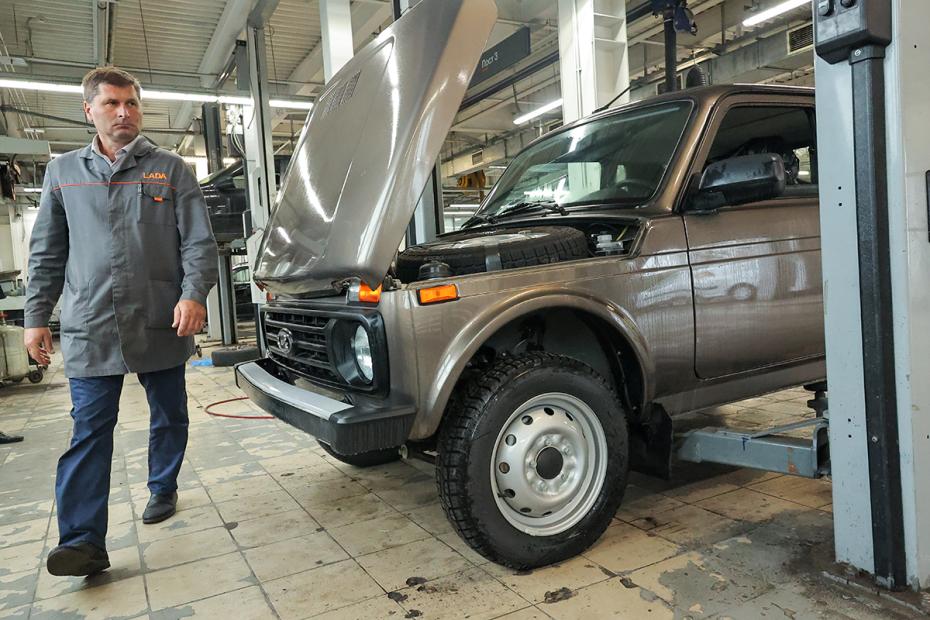 Автослесарь проводит техническое обслуживание автомобиля при автосалоне дилерского центра Lada
