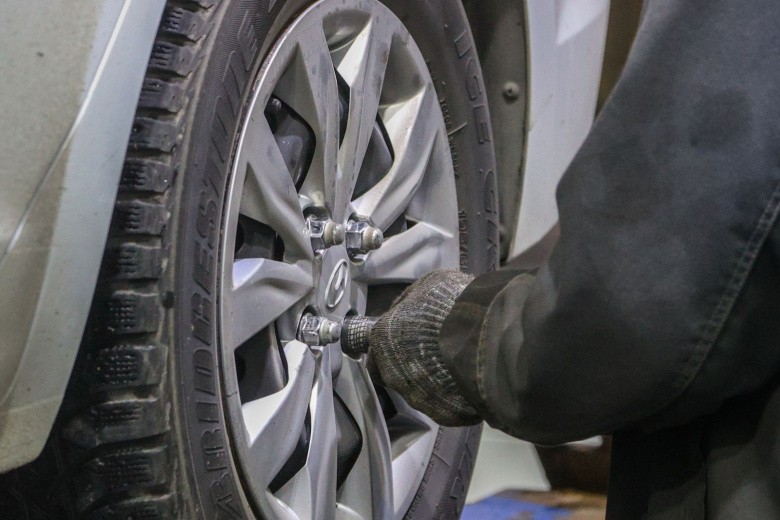 Работник автосервиса занимается шиномонтажом