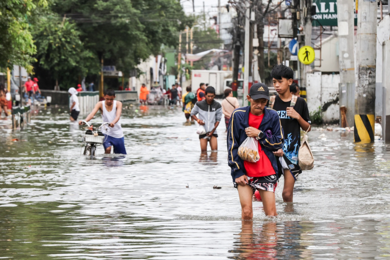 Жители города Навотас, Филиппины, пробираются сквозь паводковые воды, 10 ноября 2025 г. Супертайфун «Фунг-Вонг» обрушился на провинцию Аврора в восточной части острова Лусон на Филиппинах