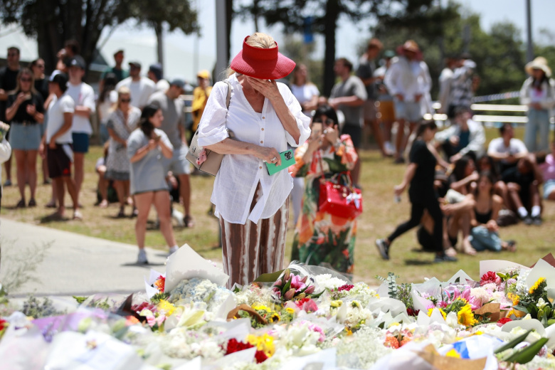 Женщина оплакивает жертв стрельбы на пляже Бонди в Сиднее, Австралия