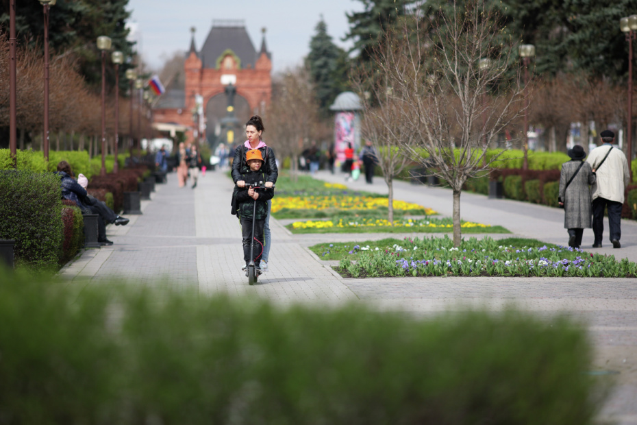 Женщина с ребенком катаются на самокате на улице Красной в Краснодаре