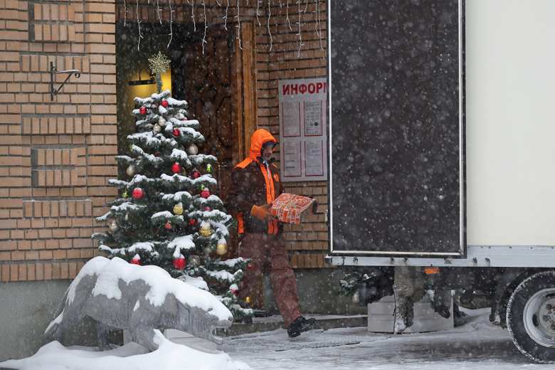 Работник транспортной компании загружает коробки в грузовой автомобиль