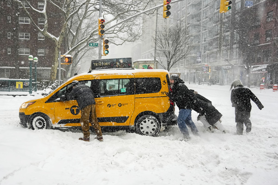 США, Нью-Йорк. Прохожие толкают такси, застрявшее в снегу