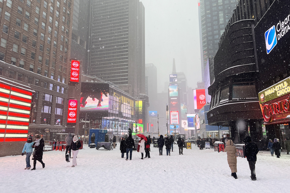 Прохожие прогуливаются по заснеженной Таймс-сквер
