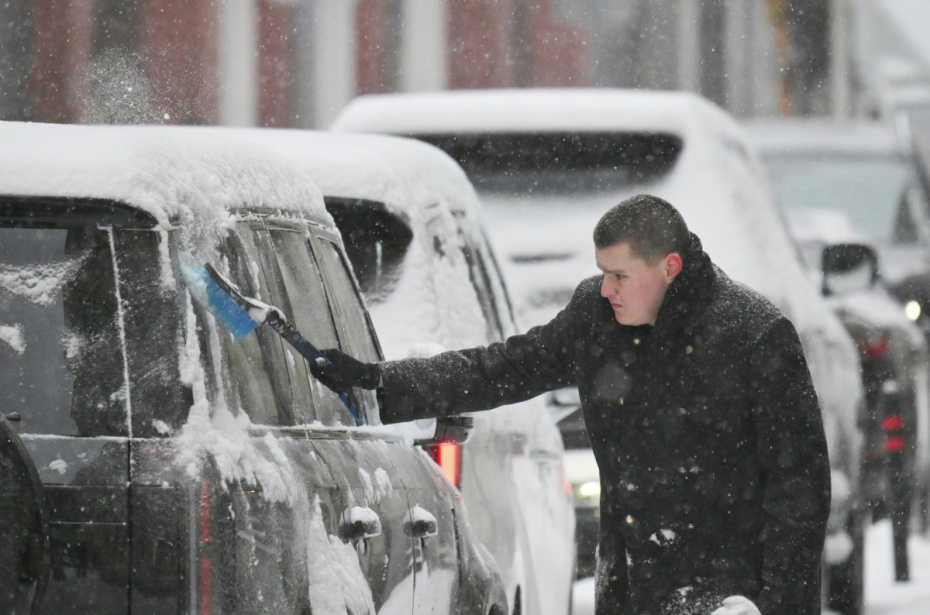 Мужчина расчищает машину от снега во время снегопада в Москве. По словам синоптиков, более трети месячной нормы осадков выпадет в Москве 27 января