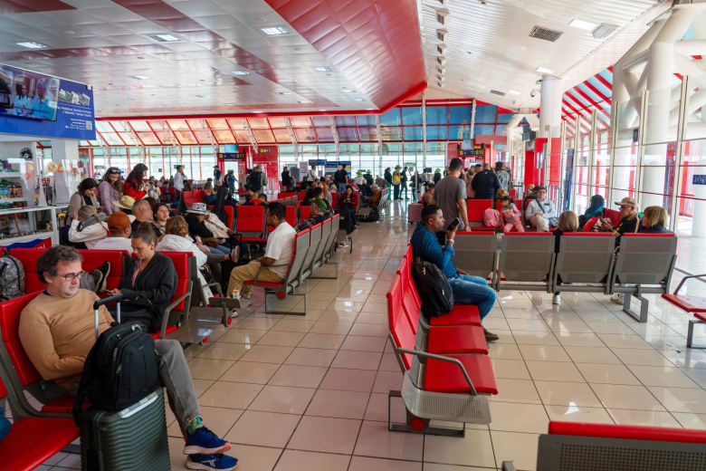 Пассажиры, сидящие в зале ожидания в международном аэропорту имени Хосе Марти. Гавана, Куба