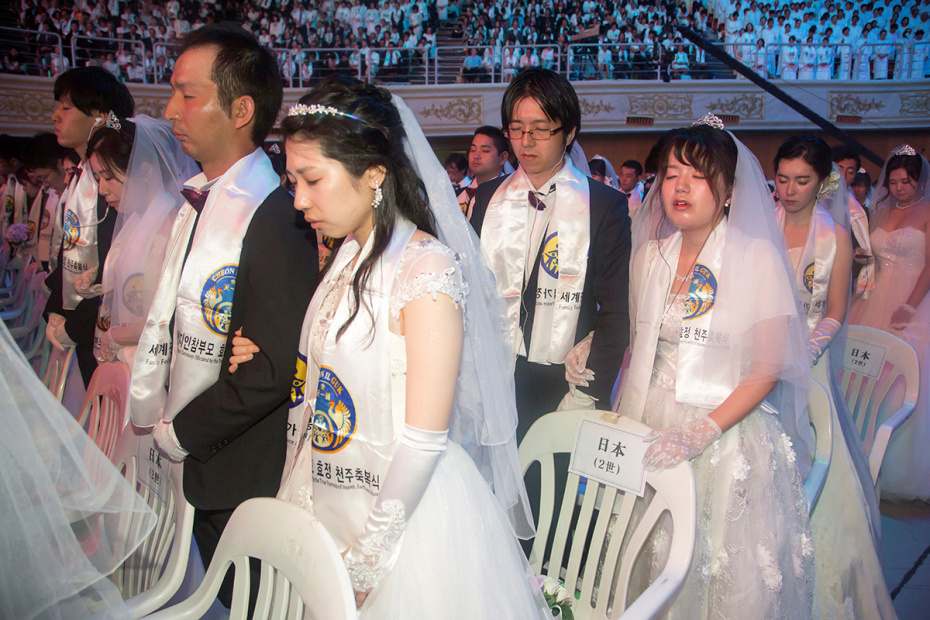 Пары из Японии молятся во время массовой свадебной церемонии Церкви Объединения