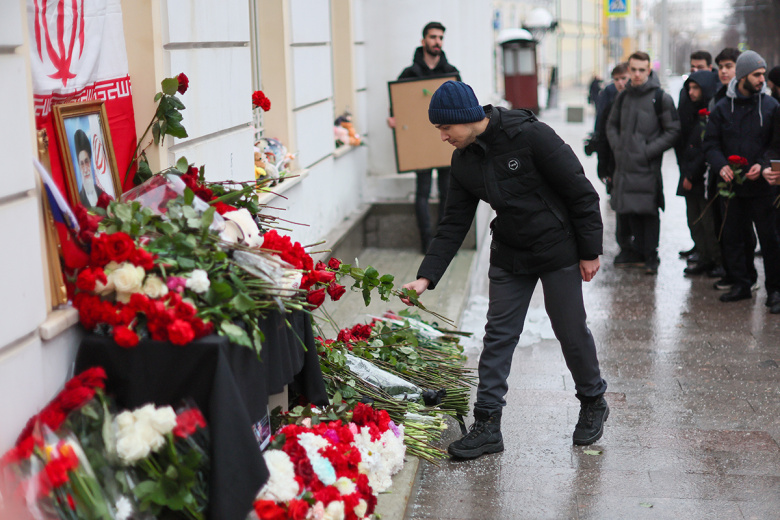 Мужчина возлагает цветы к стихийному мемориалу у посольства Ирана