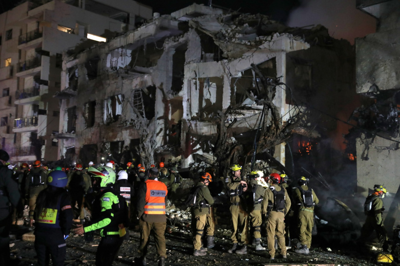 Сотрудники израильских сил безопасности и спасательных служб работают на месте попадания баллистической ракеты, выпущенной из Ирана, в Тель-Авиве, Израиль