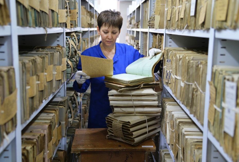 Сотрудница разбирает папки с документами в Государственном архиве Челябинской области