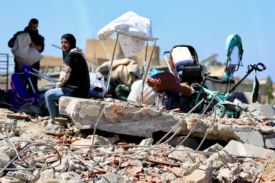 Люди ищут свои вещи среди обломков жилого дома, разрушенного в результате израильских авиаударов недалеко от Сидона, на юге Ливана