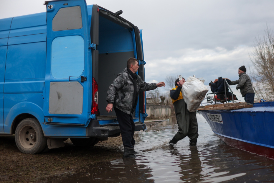 Мужчины грузят вещи и продукты в лодку на месте подтопления из-за разлива реки Оки в селе Заокское в Рязанской области.