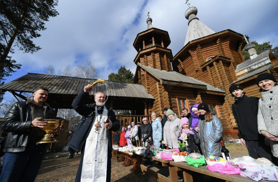 Священнослужитель освящает пасхальные яйца и куличи во дворе храма Абалакской иконы Божией матери «Знамение» в Дивногорске