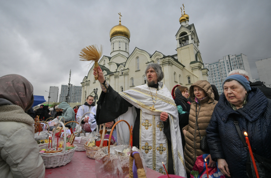 Священнослужитель освящает куличи во дворе храма преподобного Андрея Рублева в московском районе Раменки