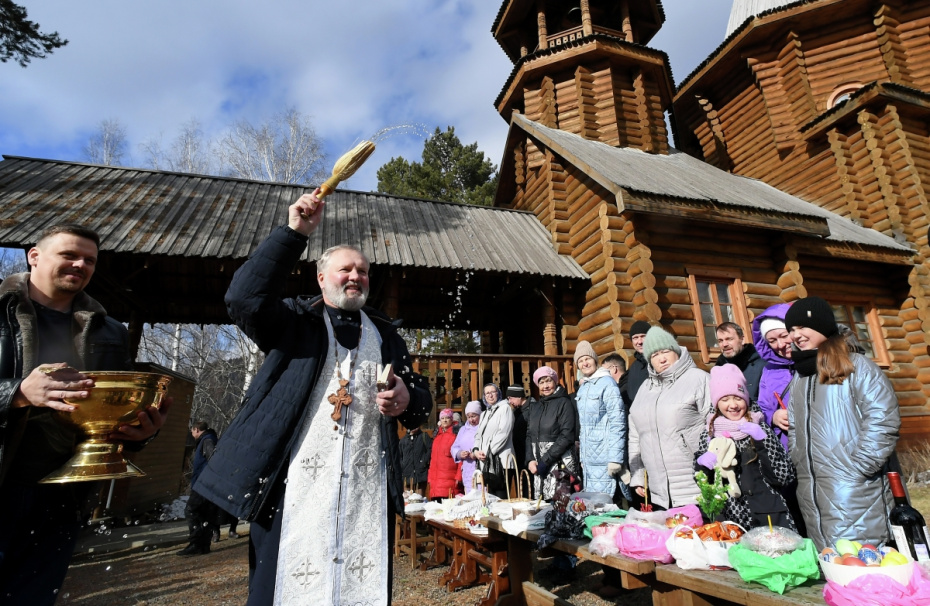Священнослужитель освящает пасхальные яйца и куличи во дворе храма Абалакской иконы Божией матери «Знамение» в Дивногорске