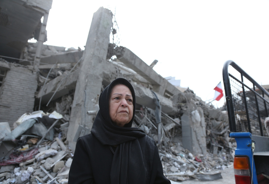 Женщина стоит перед поврежденными зданиями в Тегеране после обстрела со стороны Израиля