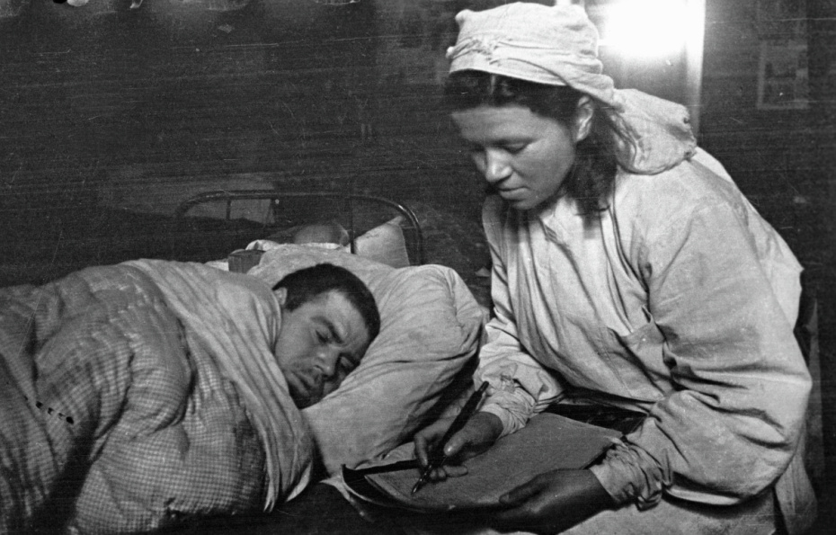 Прибалтийский фронт. Сестра медсанбата пишет письмо родным под диктовку раненого солдата