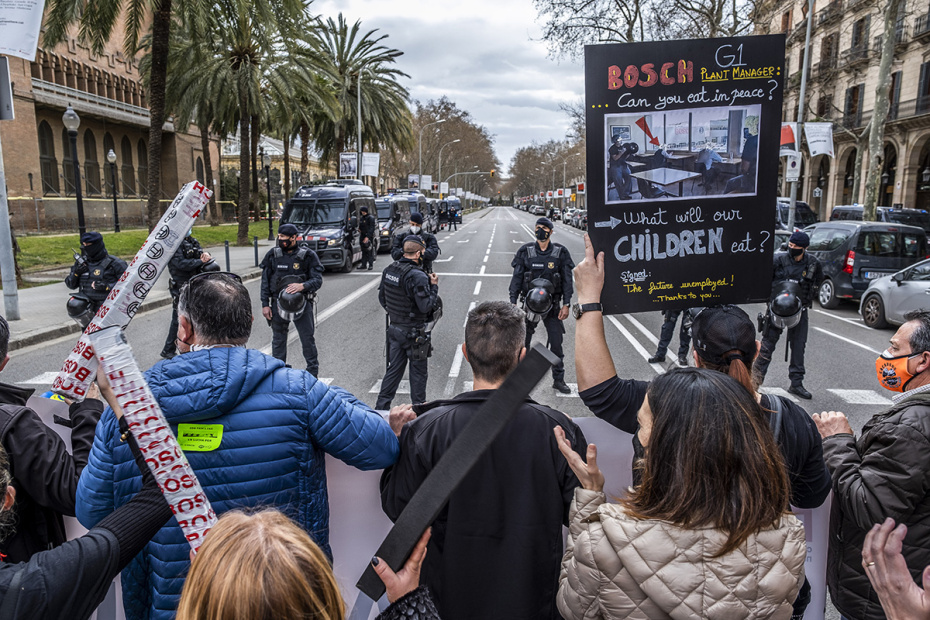 Рабочие заблокированы кордоном полицейских из Mossos d'Esquadra во время демонстрации