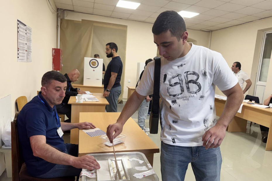 Мужчина опускает бюллетень в урну для голосования во время парламентских выборов в Армении