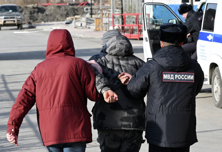 Сотрудники полиции ведут пытавшегося скрыться бегством иностранного трудового мигранта во время рейда