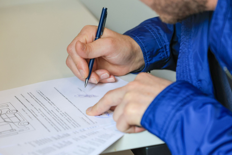 Покупатель подписывает документы о покупке автомобиля