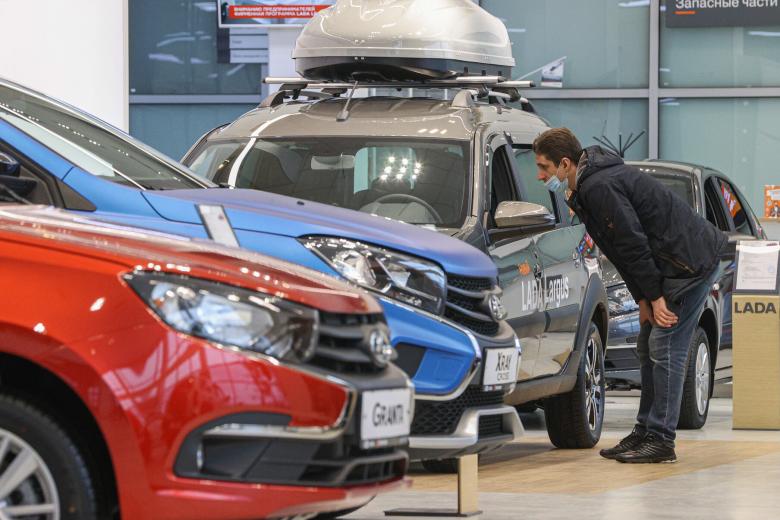 Посетители осматривают автомобиль Lada в автосалоне дилерского центра в Москве