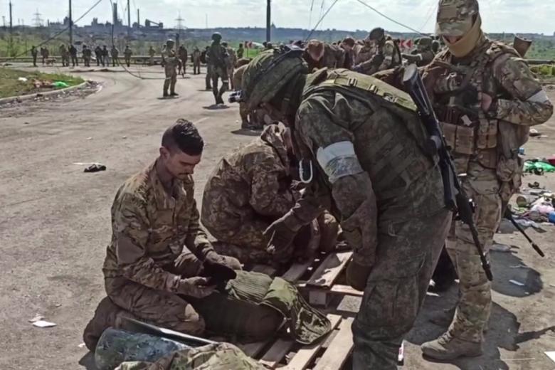 Российские военнослужащие досматривают сдавшихся в плен украинских военнослужащих и боевиков националистического батальона «Азов» на территории комбината «Азовсталь» в Мариуполе