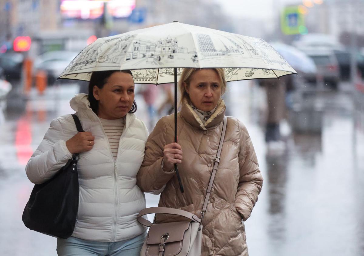 Женщины под зонтом во время дождя в городе весной