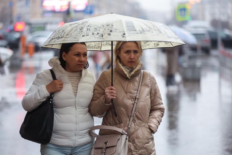 Женщины под зонтом во время дождя в городе весной