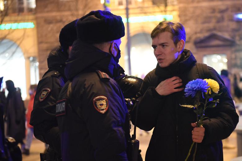 Москва. Сотрудники полиции и участник несогласованной акции против спецоперации на Украине на Пушкинской площади. В руках участник держит хризантемы цвета украинского флага