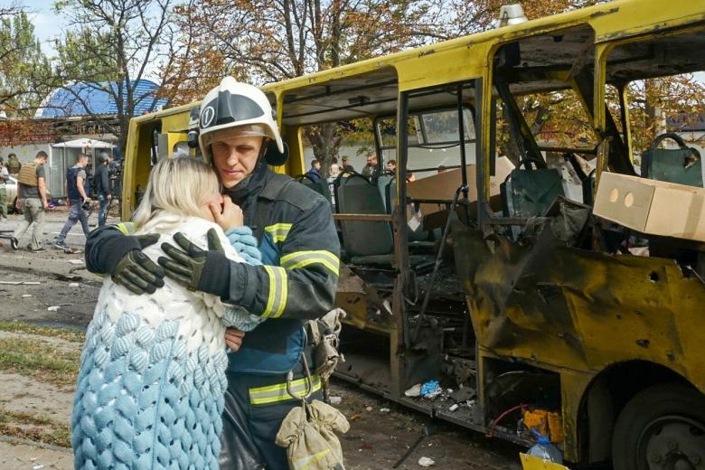 Мужчина успокаивает плачущую женщину около автобуса, который был уничтожен в результате обстрела со стороны ВСУ