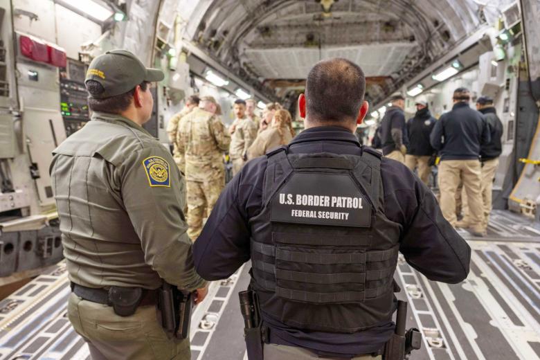 Агенты таможенной и пограничной службы США готовятся погрузить нелегальных мигрантов на транспортный самолет ВВС США C-17 Globemaster III