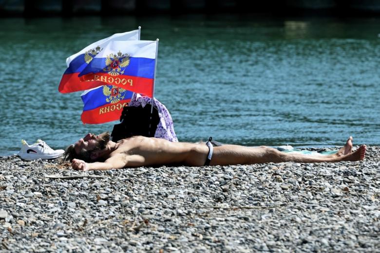 Мужчина загорает на пляже в Сочи