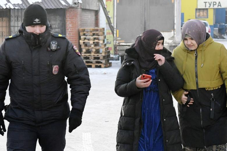 Сотрудник полиции сопровождает задержанных иностранных граждан