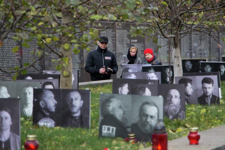 Участники мероприятий у плит с фотографиями репрессированных в «Саду памяти»