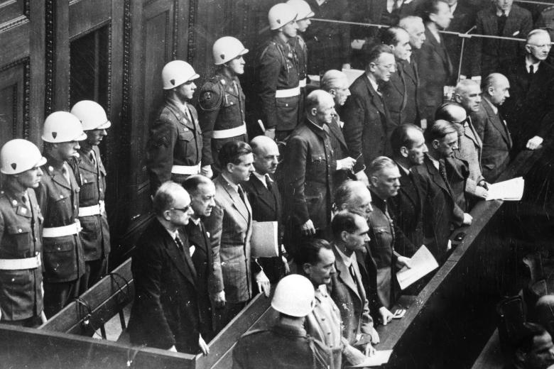 Главные обвиняемые как военные преступники нацистского режима окружены военными полицейскими на Нюрнбергском процессе в 1946 году