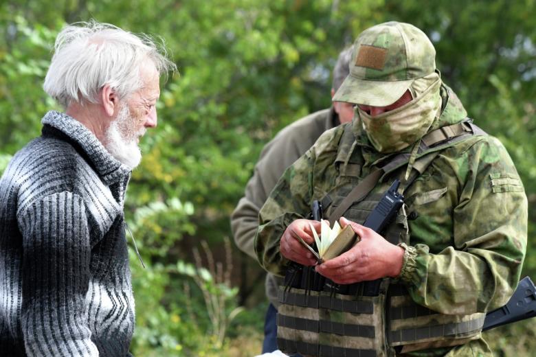 Военнослужащий проверяет документы у украинского беженца у контрольно-пропускного пункта «Васильевка» в Запорожской области