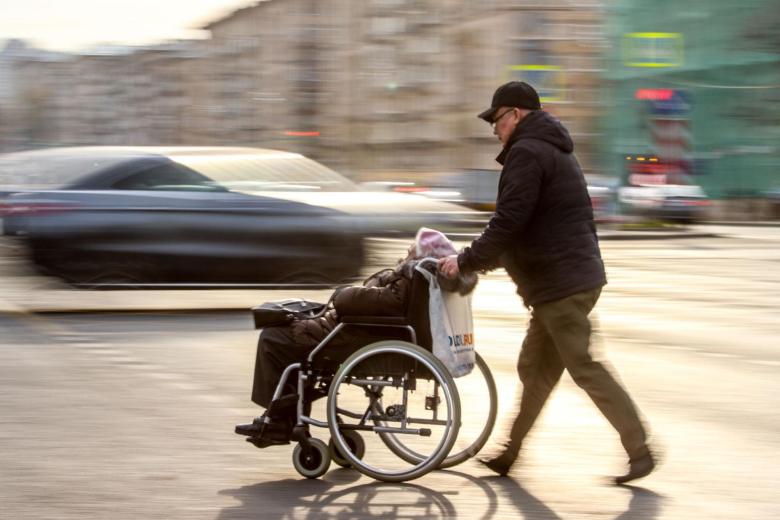 Москва. Человек везет инвалида на коляске