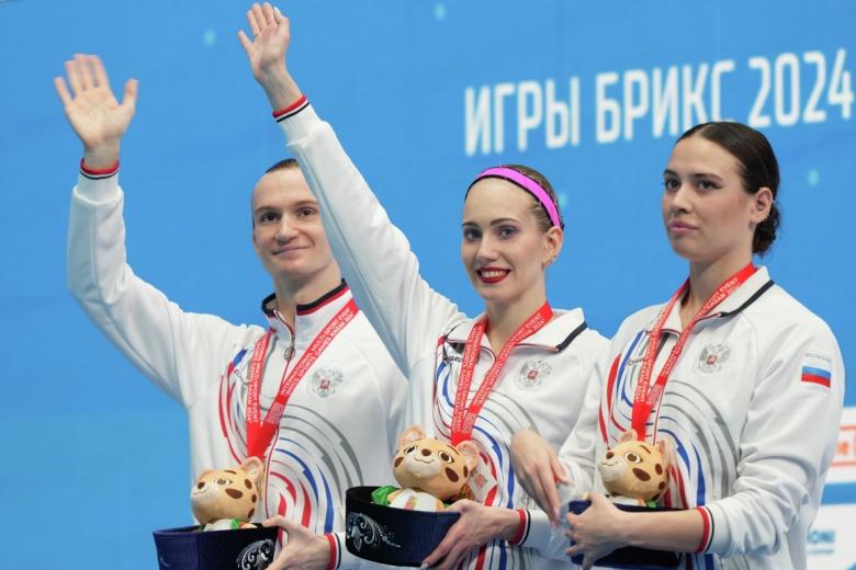 Майя Гурбанбердиева, Александр Мальцев, Олеся Платонова (Россия), занявшие первое место в произвольной программе на соревнованиях смешанных дуэтов по синхронному плаванию на Играх БРИКС в Казани, на церемонии награждения