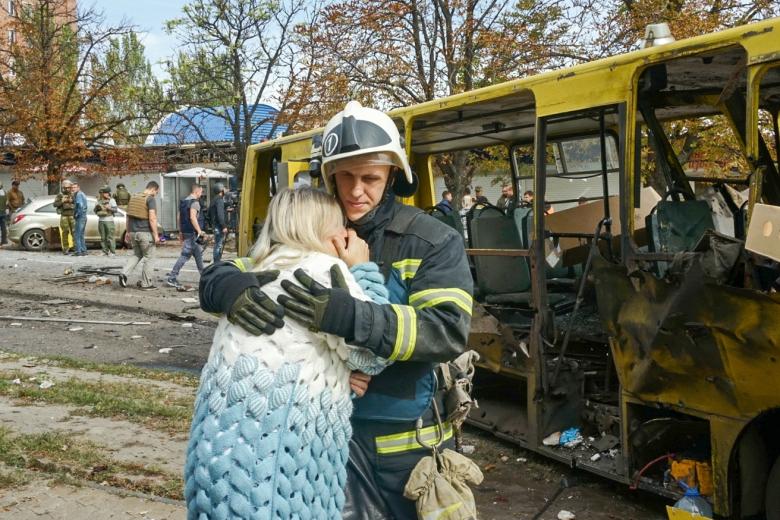 Мужчина успокаивает плачущую женщину около автобуса, который был уничтожен в результате обстрела со стороны ВСУ