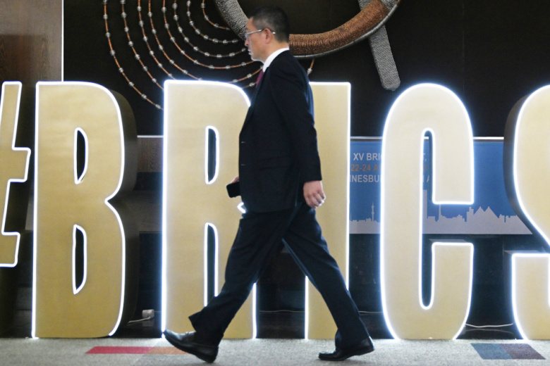 Участник бизнес-форума проходит мимо логотипа саммита БРИКС