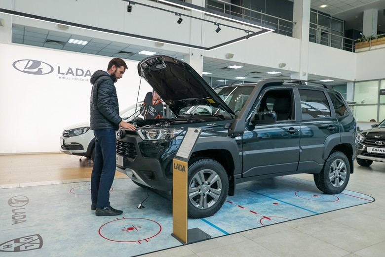 Мужчина осматривает автомобиль Niva Travel в автосалоне дилерского центра Lada