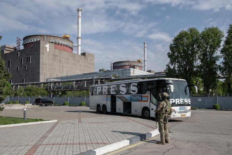 Военнослужащий ВС РФ и автобус с международной прессой на территории Запорожской АЭС в Энергодаре