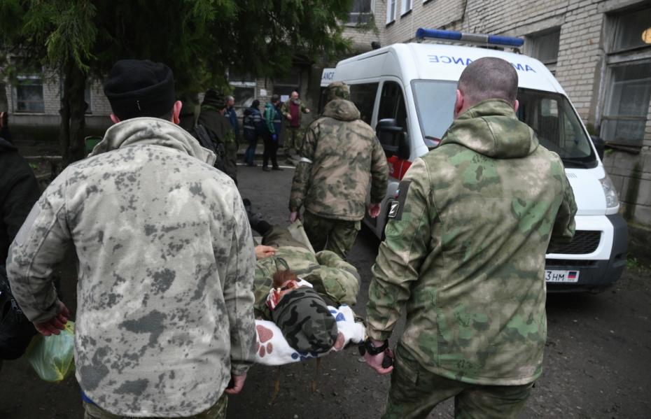 Военнослужащие переносят на носилках своего раненого сослуживца из Новоазовской центральной районной больницы для последующей эвакуации в Россию