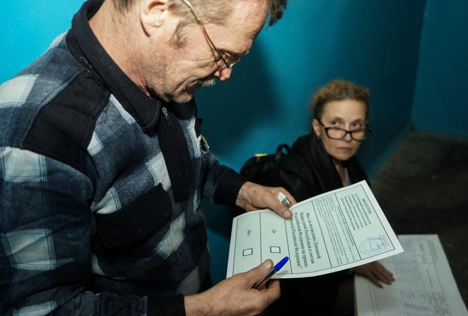 Житель Киевского района Донецка проверяет текст бюллетени