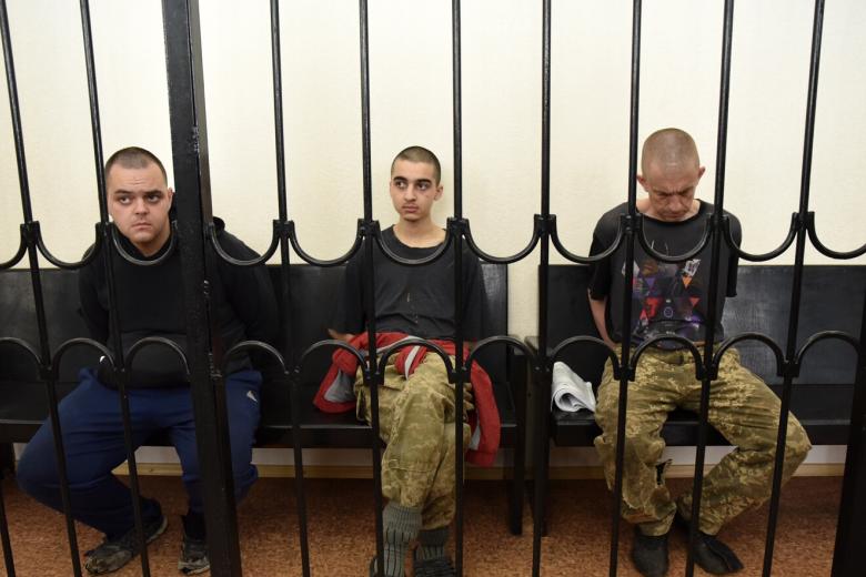 Гражданин Великобритании Эйден Эслин, гражданин Марокко Саадун Брагим и гражданин Великобритании Шон Пиннер (слева направо), обвиняемые в участии в боевых действиях в составе украинских вооруженных формирований в качестве наемников